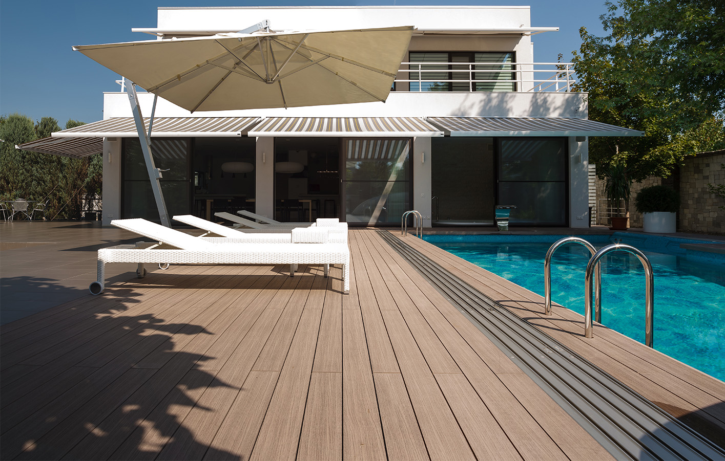 Luxuriöse Pool-Terrasse mit Holzbelag Terrasse mit Holzbelag und Pool, umgeben von stilvollen Gartenmöbeln.